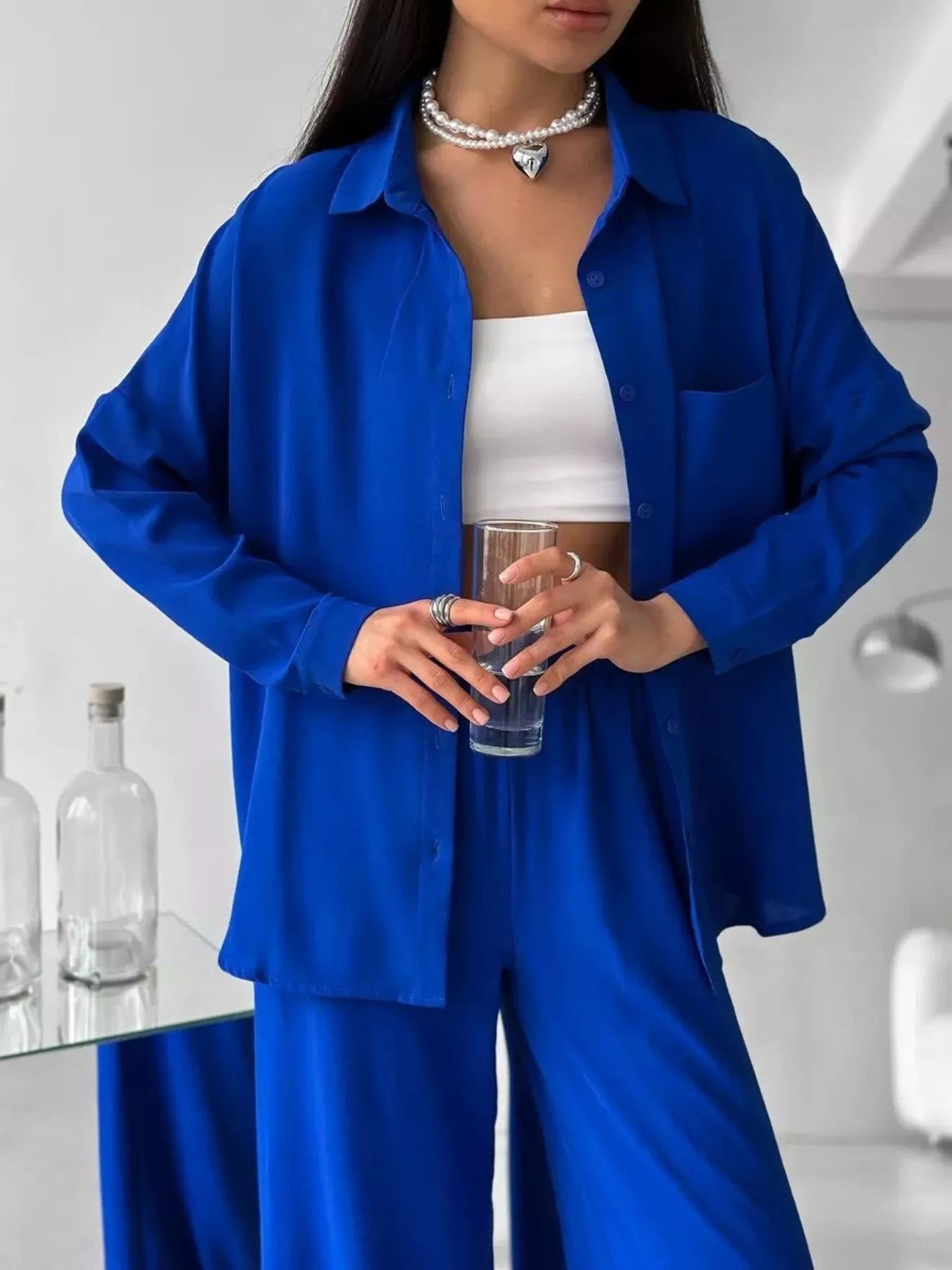 Woman wearing a blue two-piece button-down shirt and pants set with pockets.