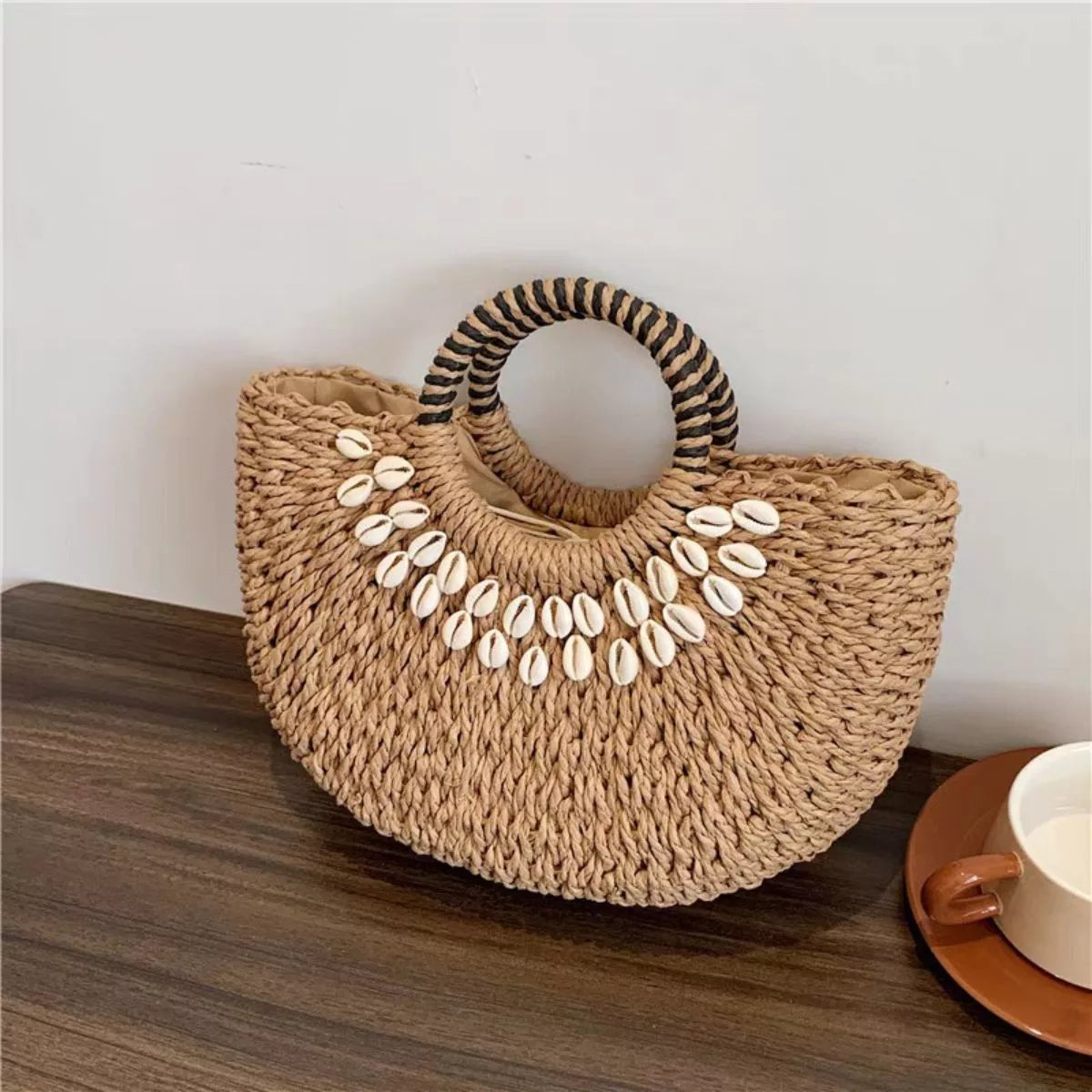 Small woven straw handbag with seashell embellishments and a short handle