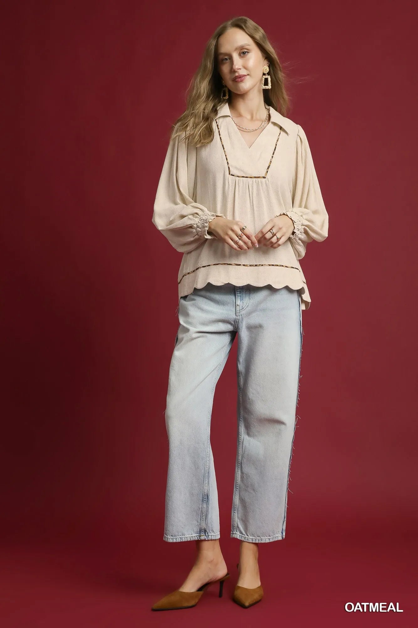 Woman modeling beige linen scallop hem blouse with contrast trim, paired with light blue jeans and brown heels.