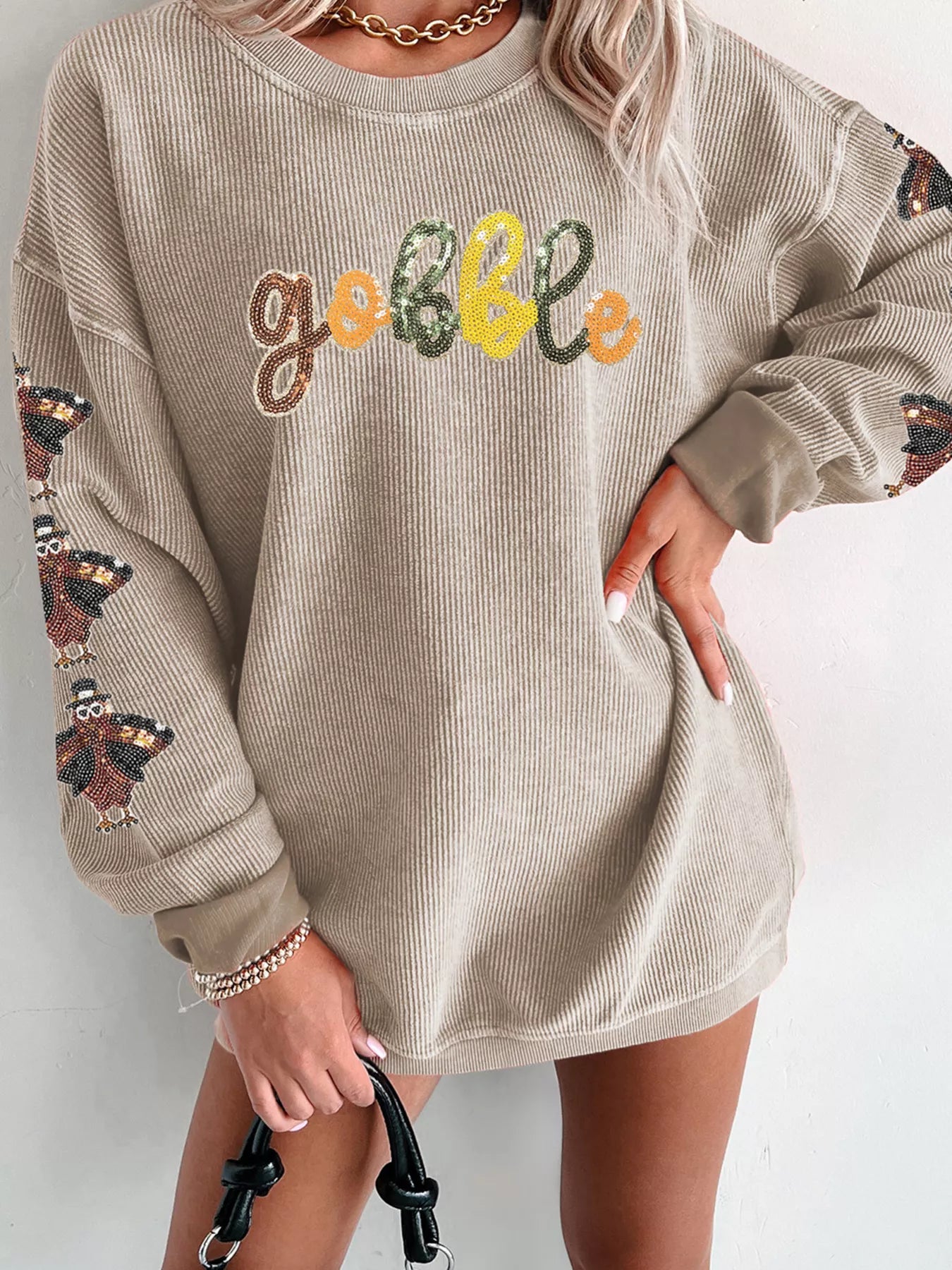 Beige ribbed sweatshirt with "Gobble" text in sequins and turkey embroidery on sleeves.