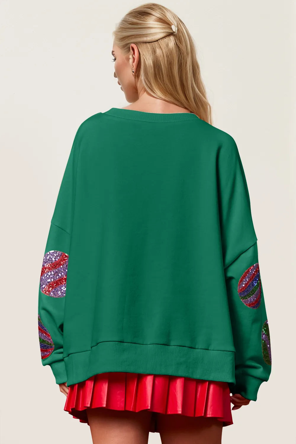 Rear view of green sequin Christmas long sleeve sweatshirt on model with red skirt.