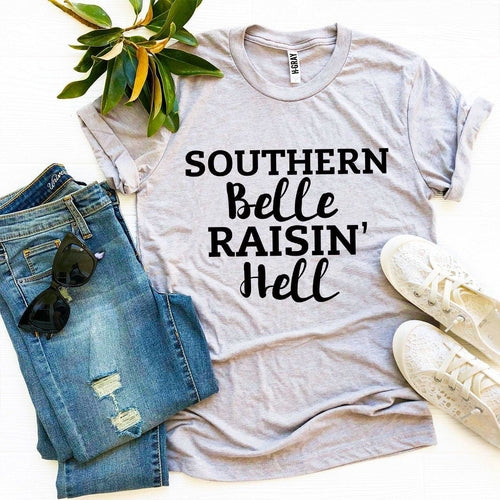 Gray Bella Canvas t-shirt with "Southern Belle Raisin' Hell" text, styled with jeans, sunglasses, and white sneakers.