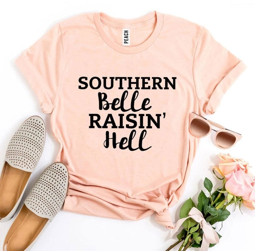 Pink Bella Canvas T-shirt with "Southern Belle Raisin' Hell" text, styled with espadrilles, sunglasses, and roses.
