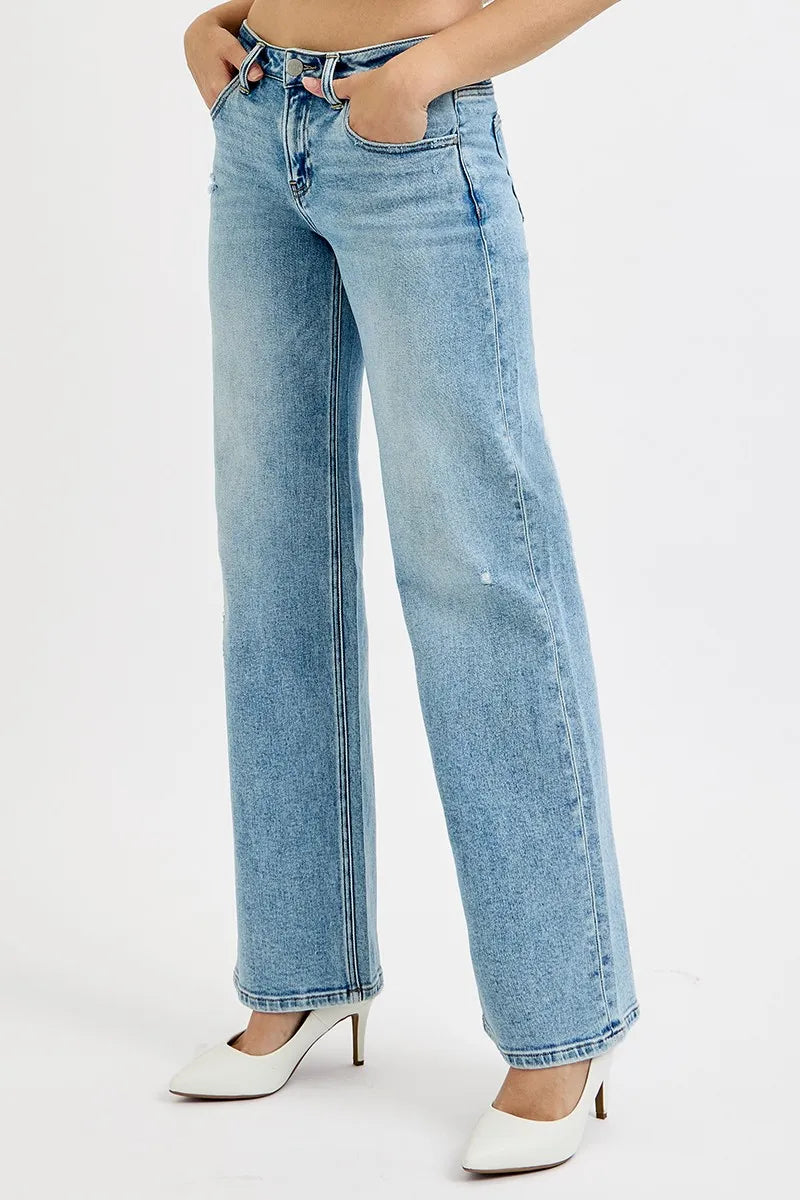 Light wash wide leg flare boyfriend jeans on a plus-size model with hands in pockets.