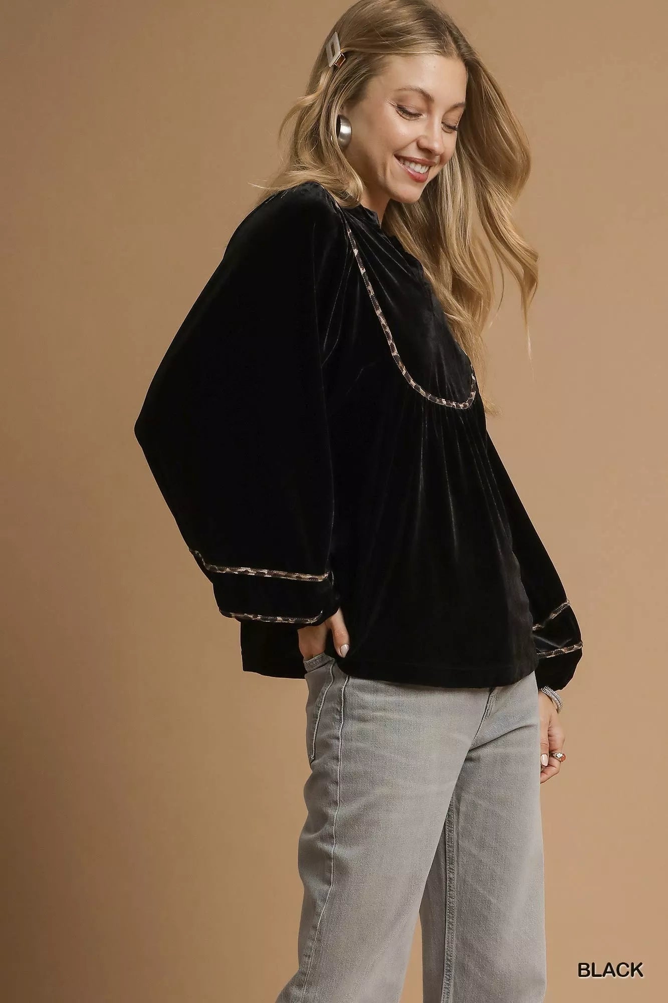 Black velvet long-sleeve blouse with gold contrast trim on a model.