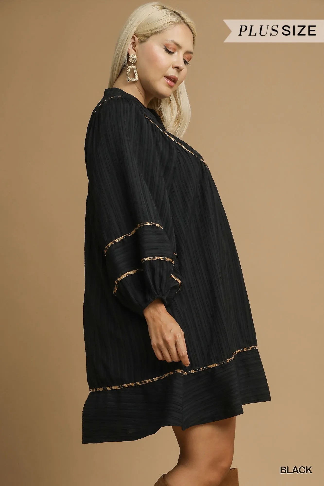 Plus-size black textured babydoll dress with leopard trim, modeled side view.