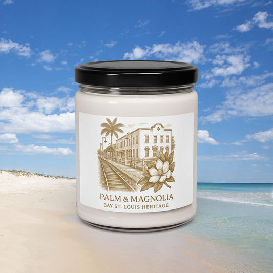 A soy candle in a glass jar with a label depicting Bay St. Louis heritage, palm, and magnolia motifs.